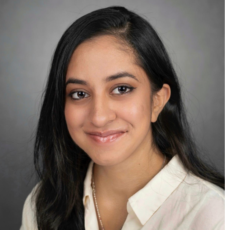 Woman with long black hair and white collared shirt smiling at the camera.